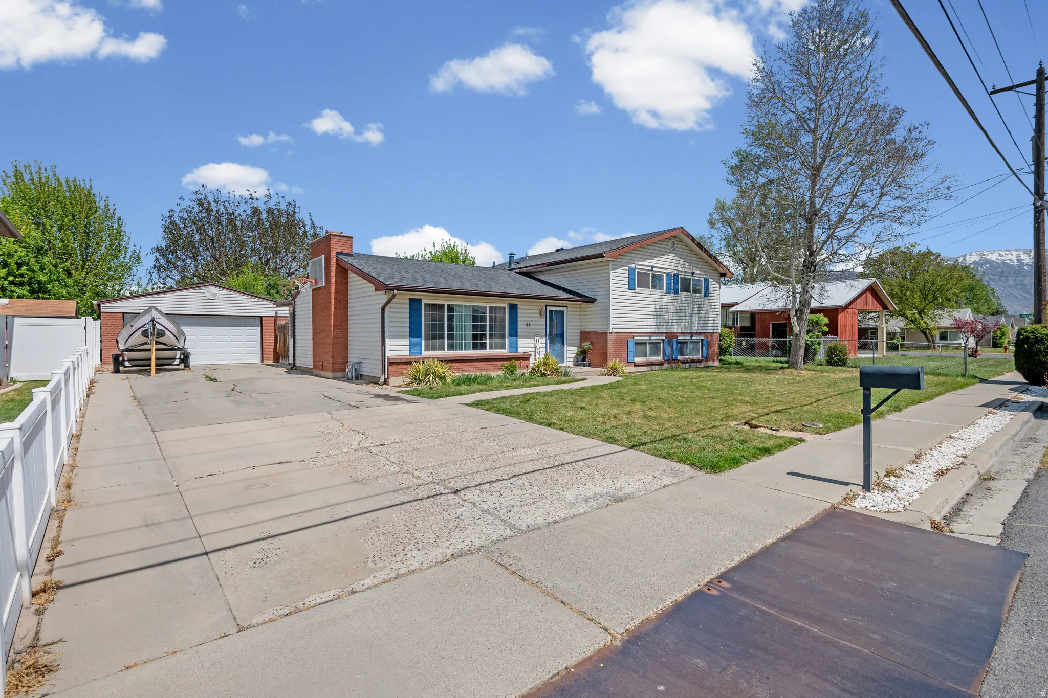 Tri-level home with a garage, an outdoor structure, brick siding, and a chimney
