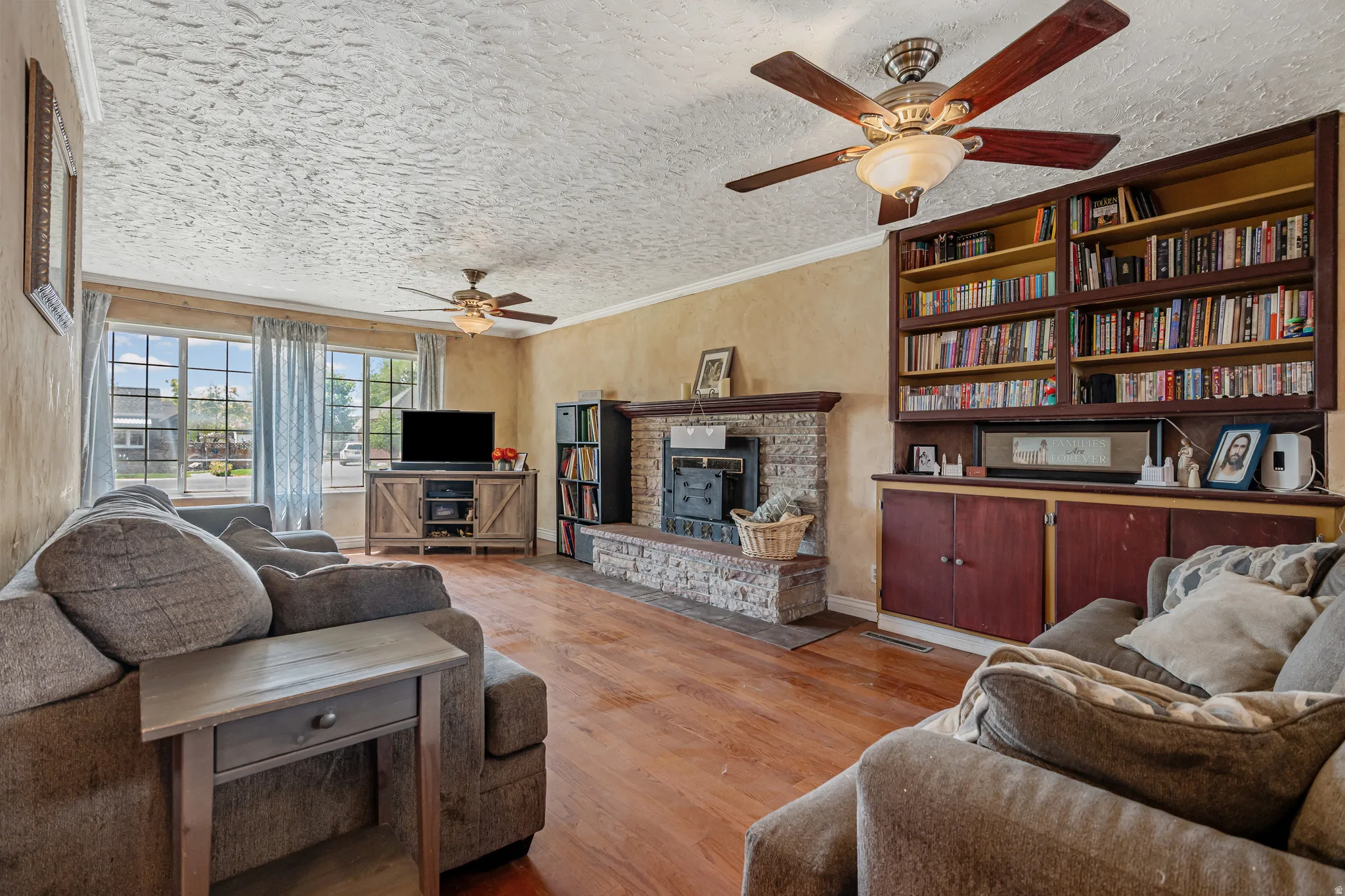 Living area featuring crown molding, a ceiling fan, wood finished floors, and a textured ceiling