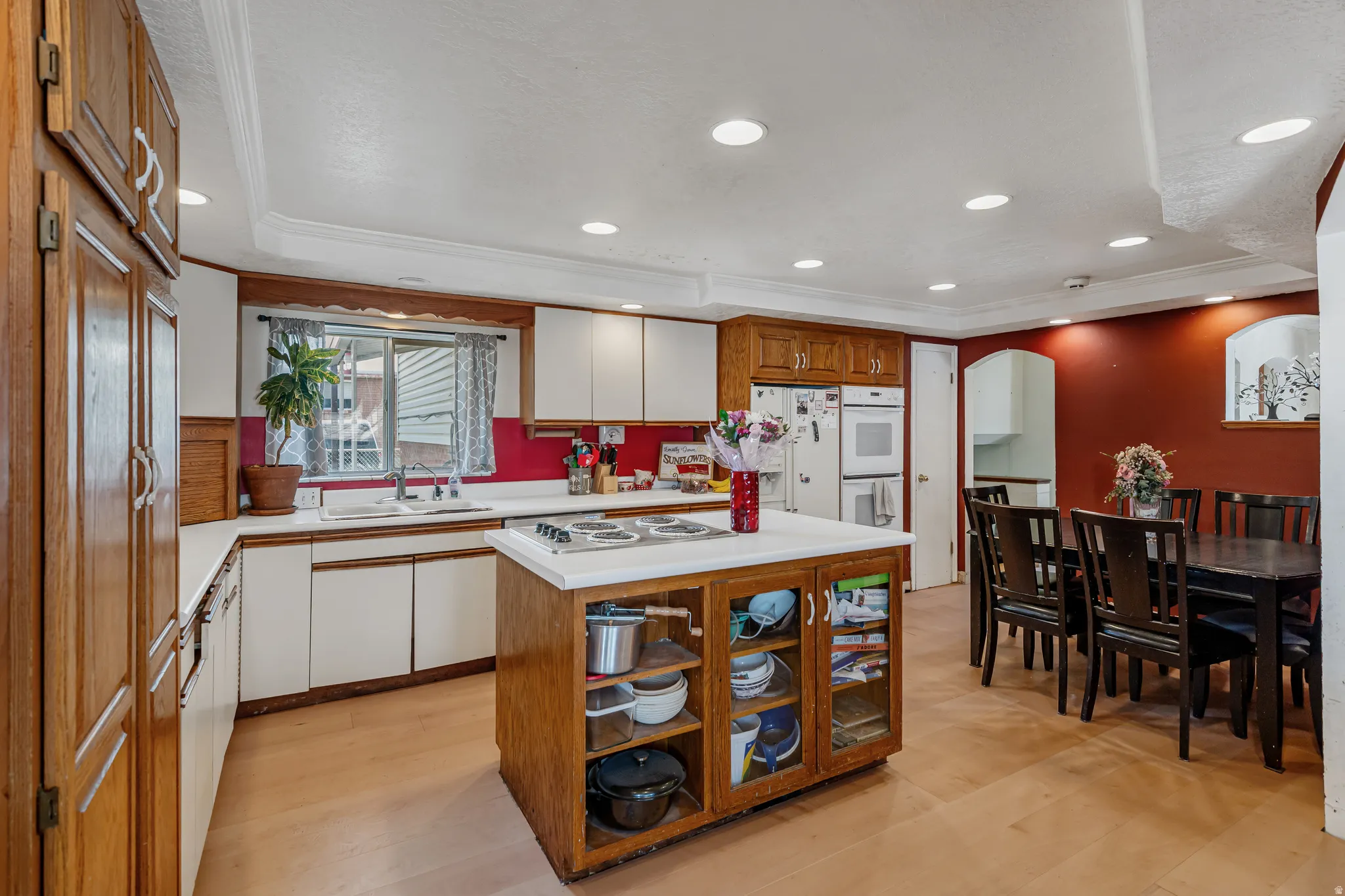 Kitchen featuring a kitchen island, arched walkways, light countertops, recessed lighting, and ornamental molding