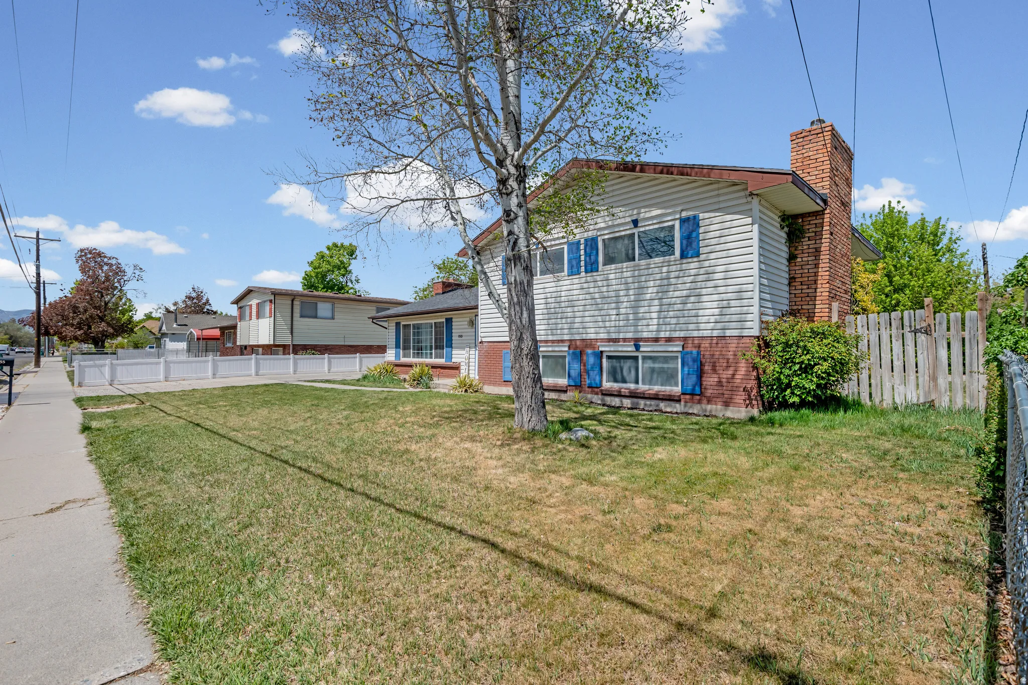 Rear view of property featuring a chimney and brick siding