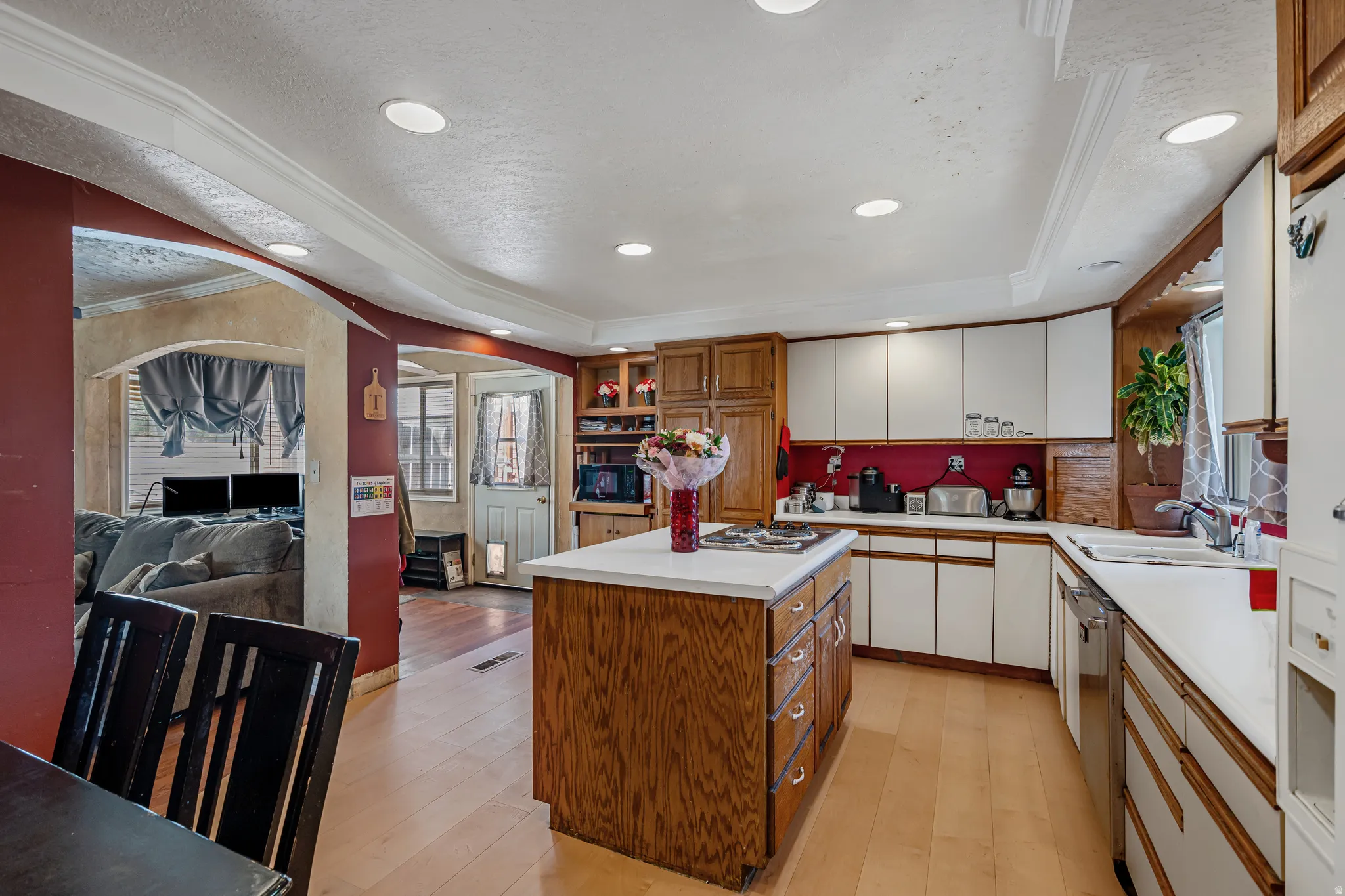 Kitchen featuring light countertops, a tray ceiling, two tone color scheme, light wood-type flooring, and a center island