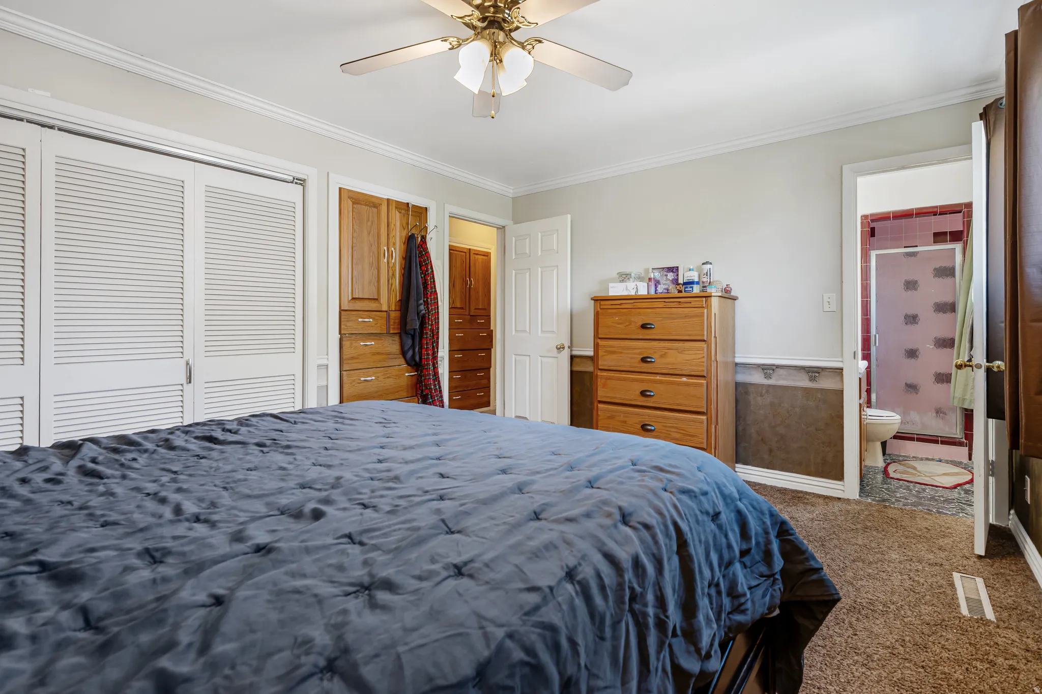 Bedroom with carpet flooring, a closet, crown molding, ceiling fan, and connected bathroom