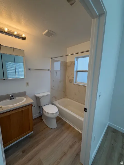 Full bathroom with vanity, dark wood-style floors, and  shower combination