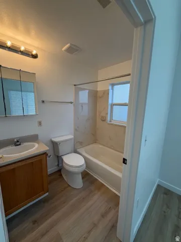 Full bathroom with vanity, dark wood-style floors, and  shower combination