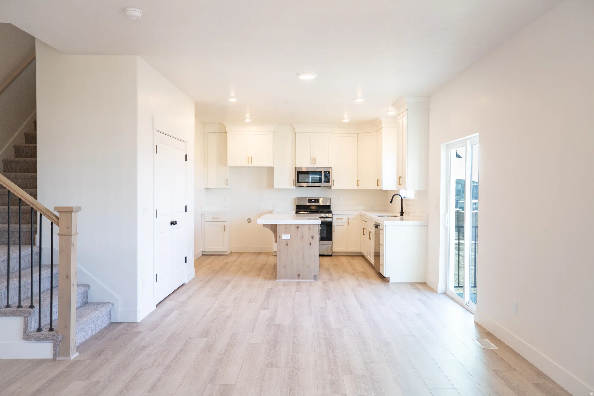 Kitchen with quartz countertops, stainless steel appliances, upgraded cabinets, and wood laminate flooring