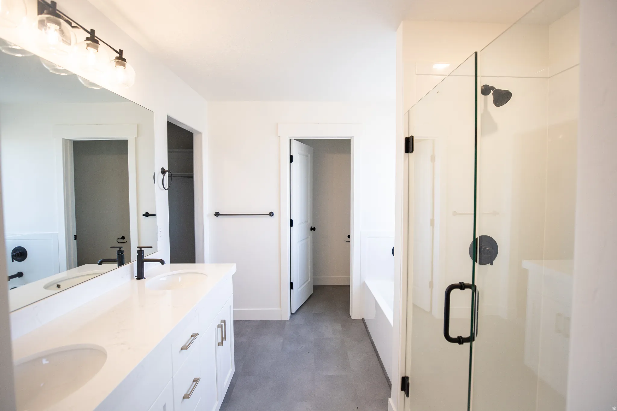 Primary bathroom featuring a separate tub and shower, double vanity, and quartz counters