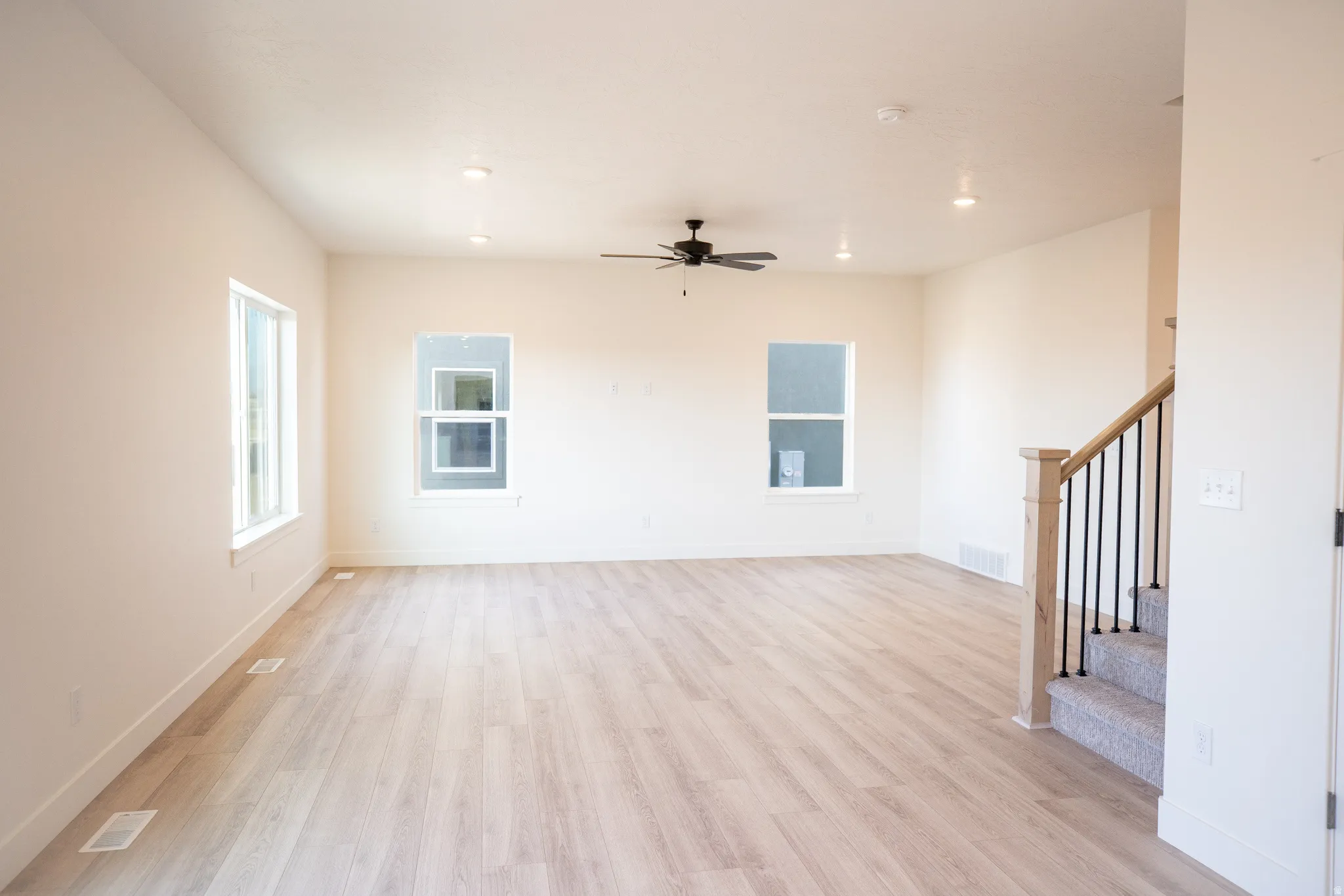 Large family room with wood laminate floors, a ceiling fan, and recessed lighting