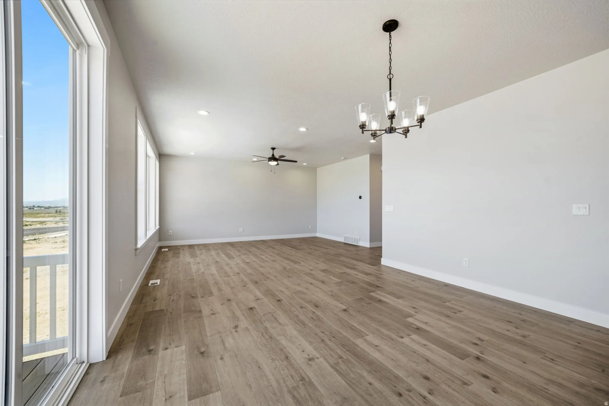 Bright interior space featuring wood-finish flooring, a contemporary chandelier, recessed lighting, and a ceiling fan
