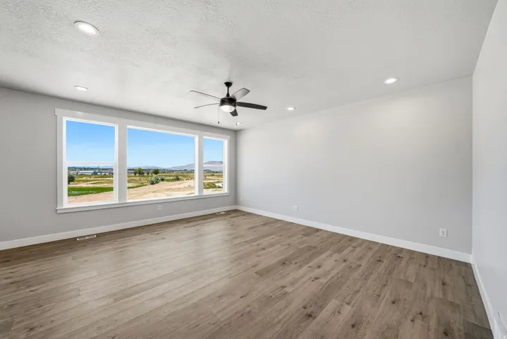 Expansive triple window offering extensive natural scenery, paired with recessed lighting, a ceiling fan, and wood-finish flooring
