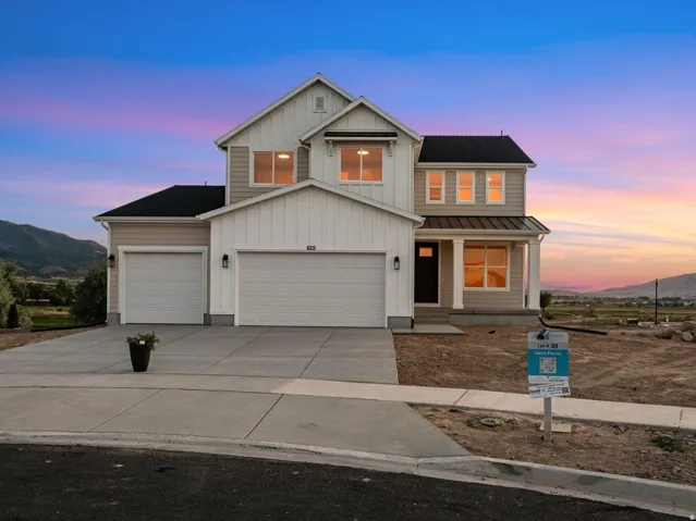 Two-story residence featuring light-toned siding, a multi-car garage, and a covered front porch with white columns