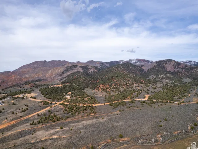 Expansive landscape featuring distant mountains, natural vegetation, and unpaved roads