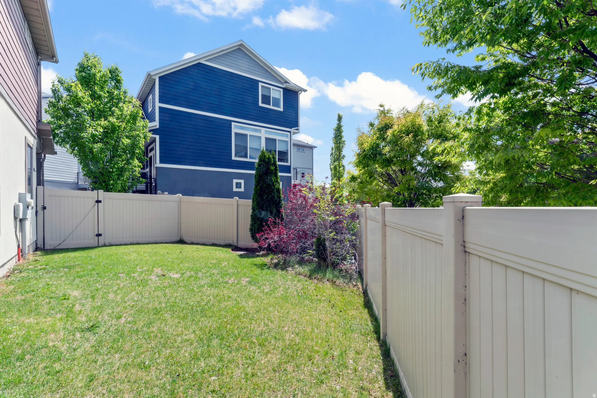 Expansive grassy lawn bordered by a tall, light-colored privacy fence