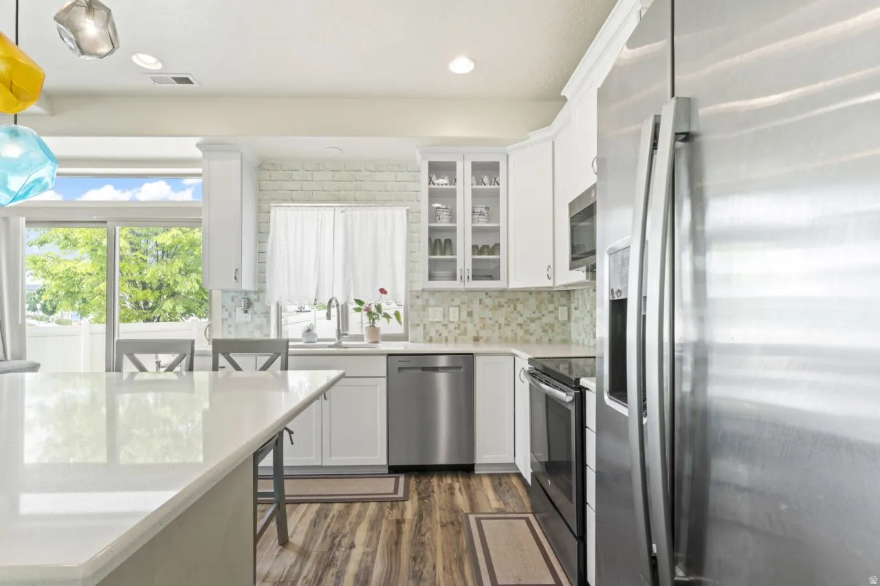Kitchen with stainless steel appliances, white cabinetry, a breakfast bar, and hanging light fixtures