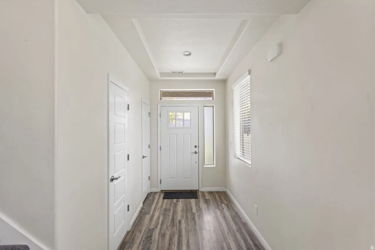 Doorway to outside featuring wood finished floors and a tray ceiling
