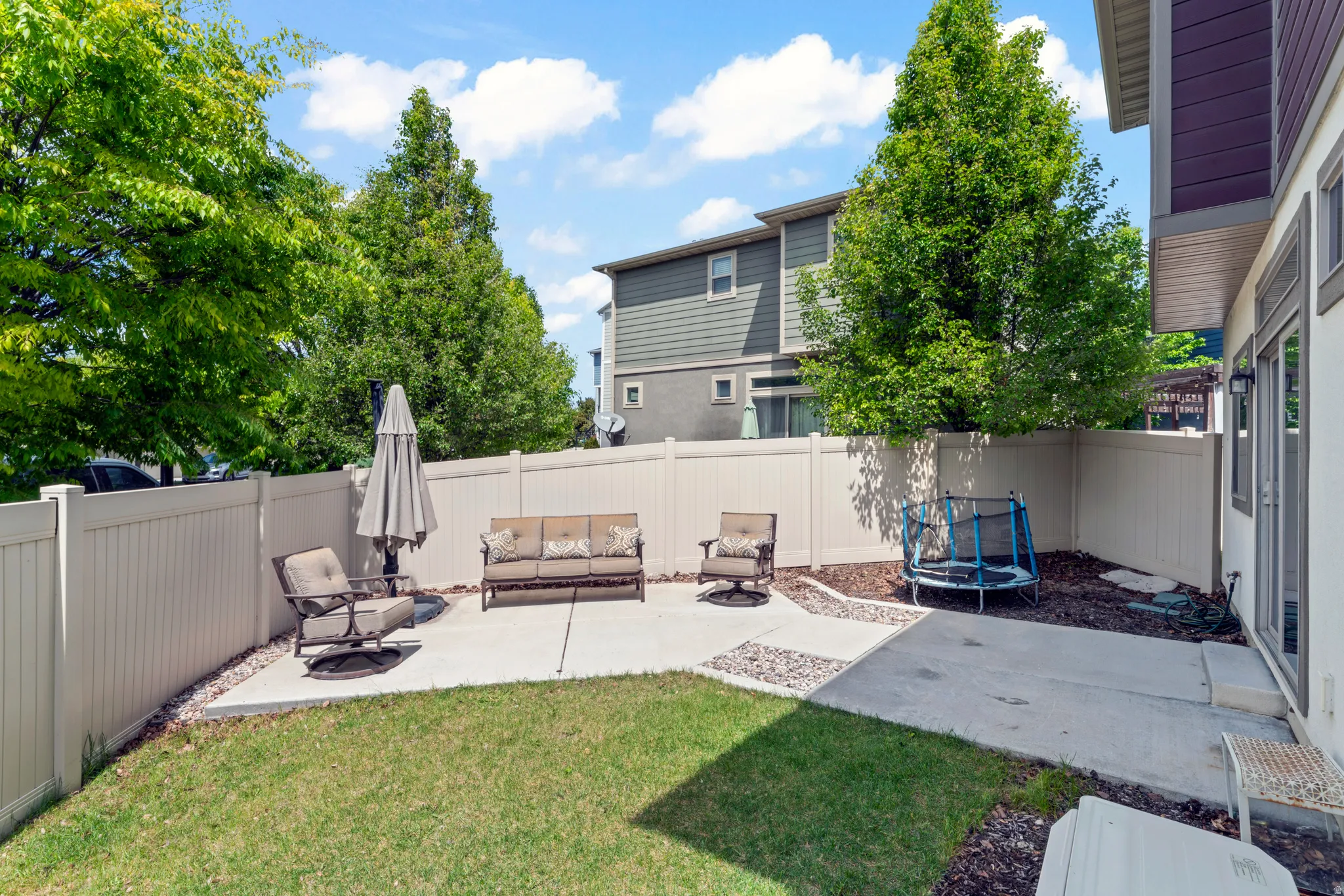 Private fenced yard featuring a concrete patio, landscaped areas, and a grass lawn