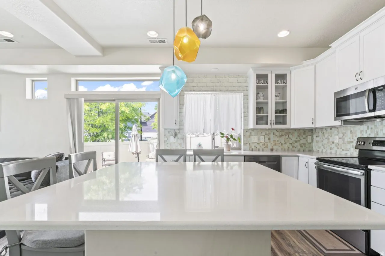 Kitchen featuring a breakfast bar area, stainless steel appliances, white cabinets, and light stone countertops