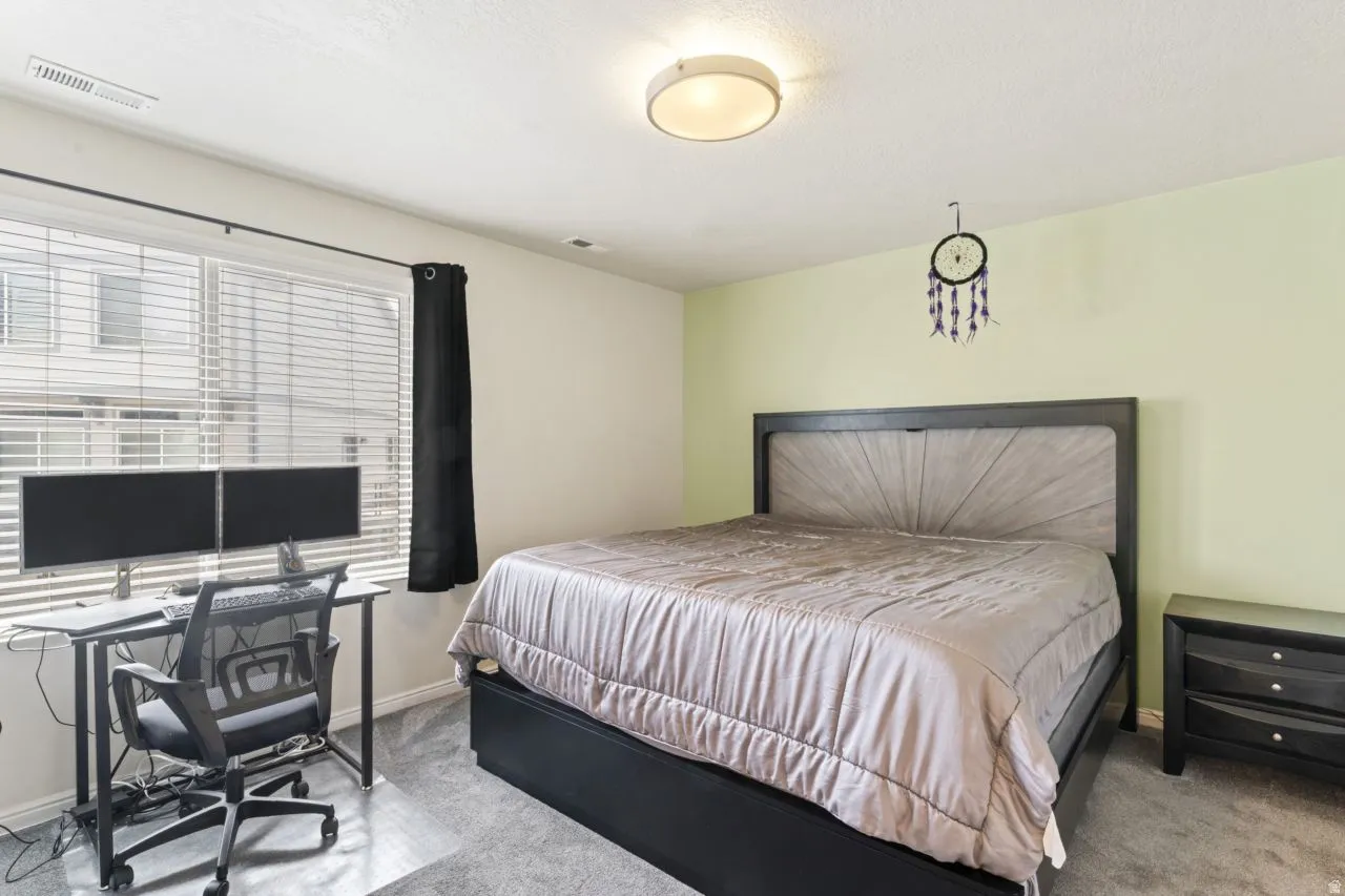 Carpeted bedroom with a desk and baseboards