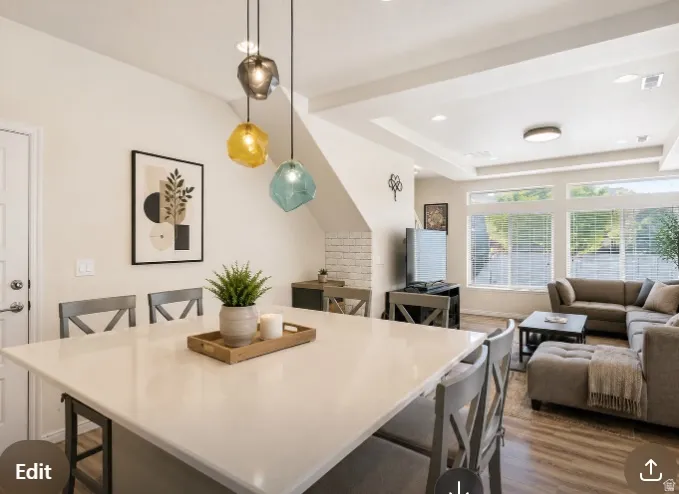 Open-concept living space featuring a substantial kitchen island with a light-toned countertop, wood-finish flooring, recessed lighting, and a white paneled door (virtually Staged)