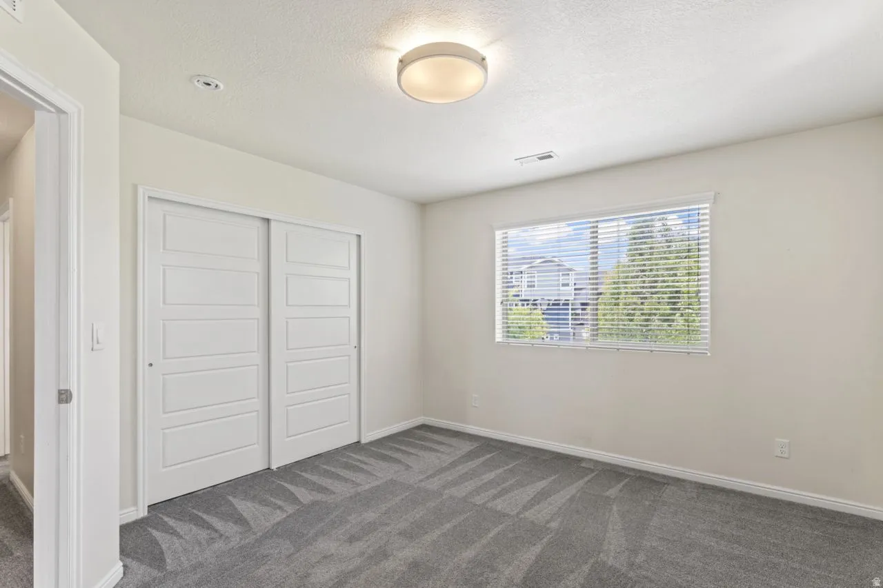 Unfurnished bedroom featuring dark colored carpet, a closet, and a textured ceiling