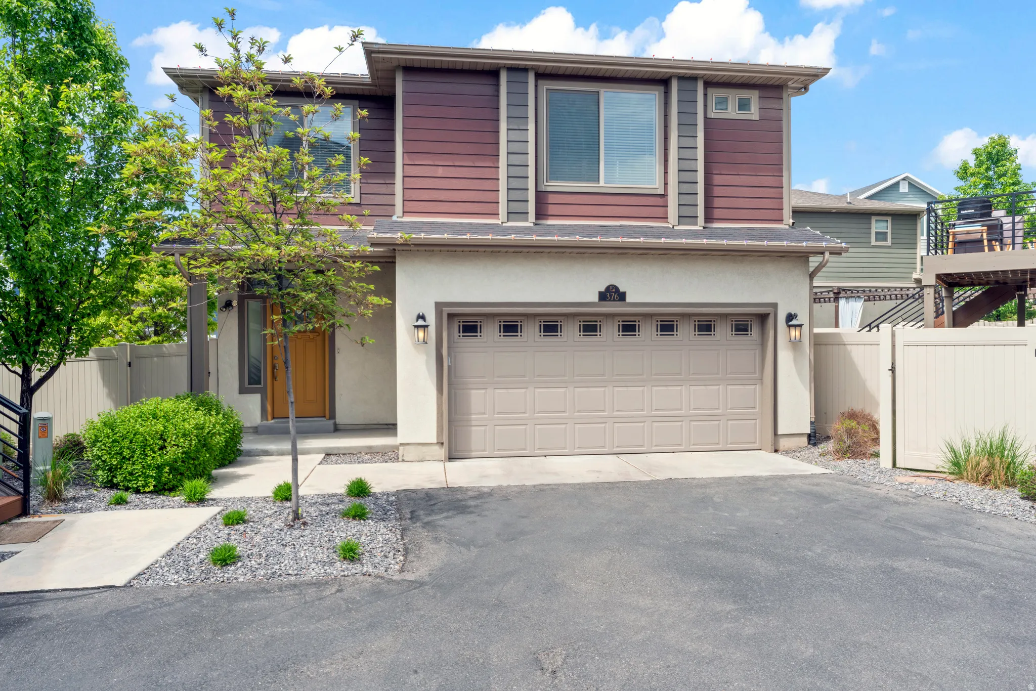 Contemporary facade featuring diverse siding materials, an integrated two-car garage, and a light-toned wood-finish entry door