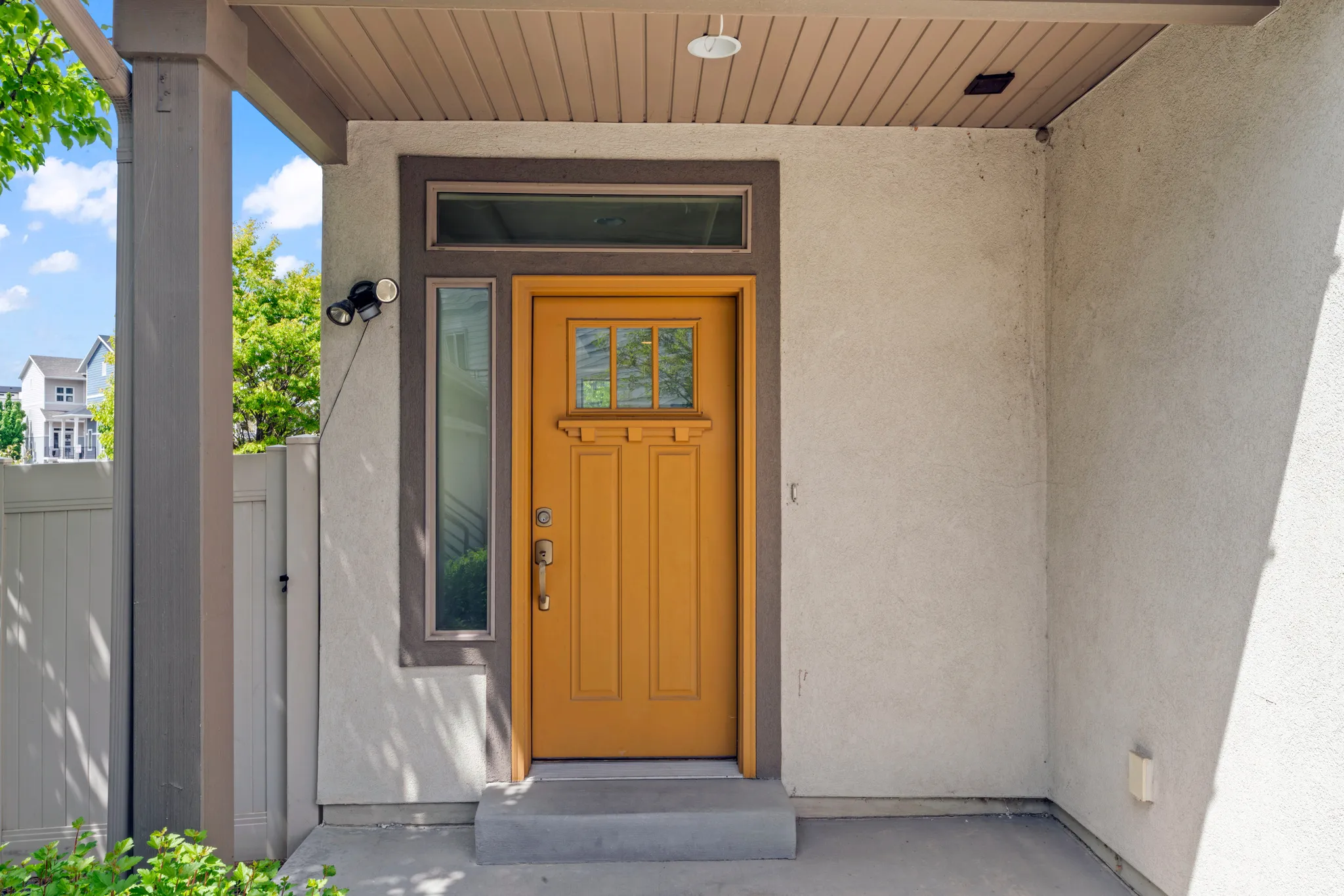 Inviting entryway featuring a warm wood-finish front door with glass panels, complemented by a transom window and a sidelight window