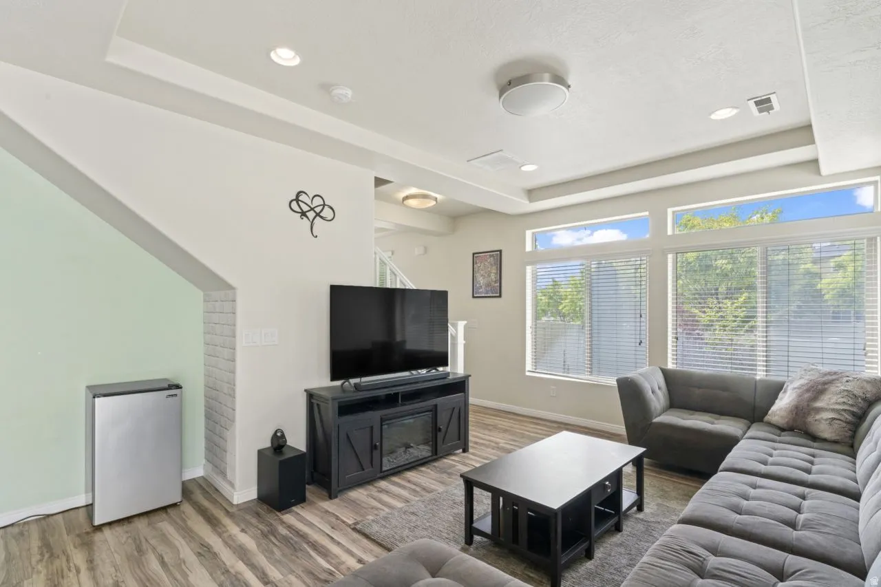 Living area featuring a raised ceiling, wood finished floors, and recessed lighting