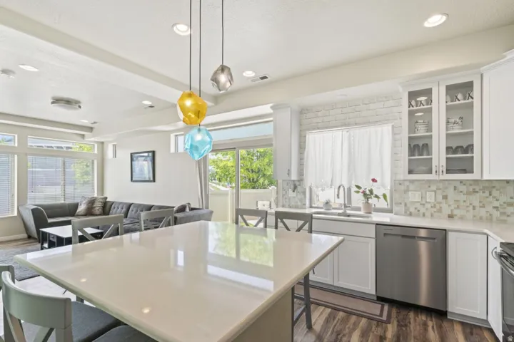Kitchen with a breakfast bar area, dark wood finished floors, white cabinetry, decorative light fixtures, and stainless steel appliances