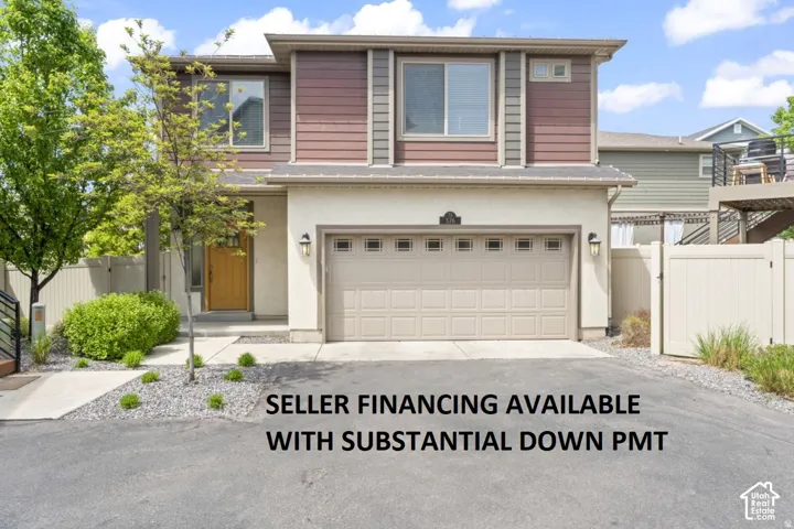 Two-story exterior with multi-tone horizontal siding, an attached garage, a concrete driveway, and a light-colored entry door