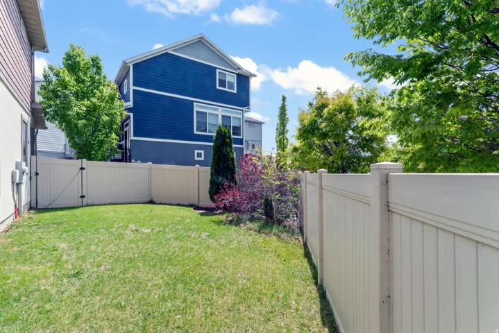 Expansive grassy lawn bordered by a tall, light-colored privacy fence