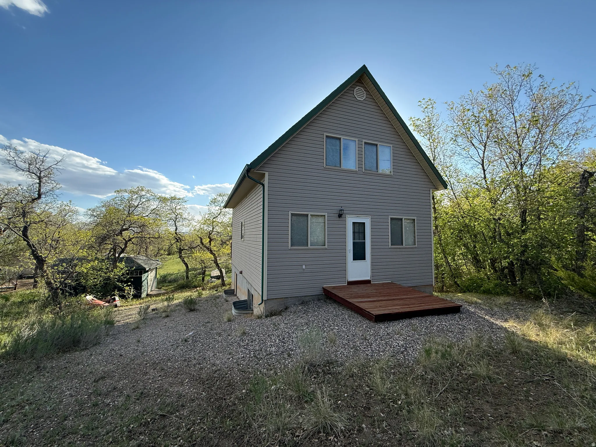Two-story residence featuring light gray siding and a dark green gable roof