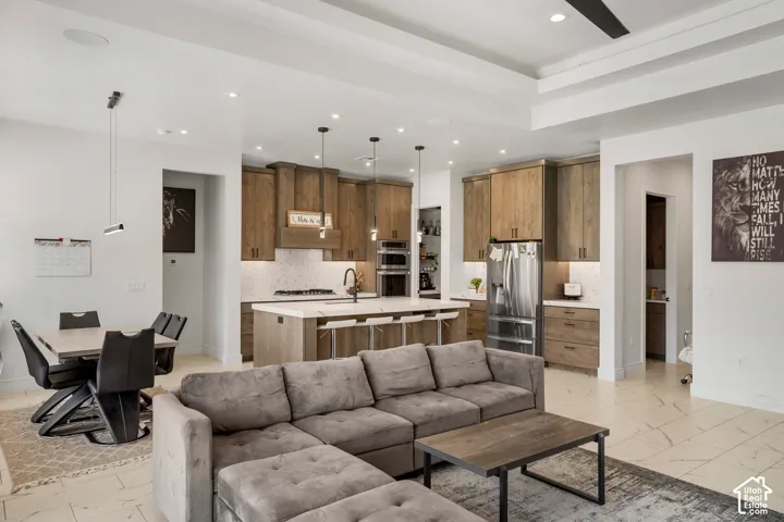 Living area with light marble finish flooring, a raised ceiling, a ceiling fan, and recessed lighting