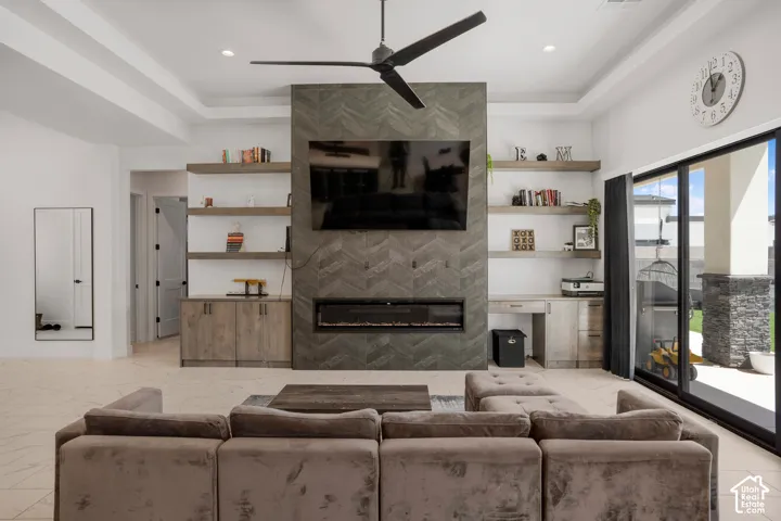 Living area featuring a fireplace, ceiling fan, and light marble finish flooring