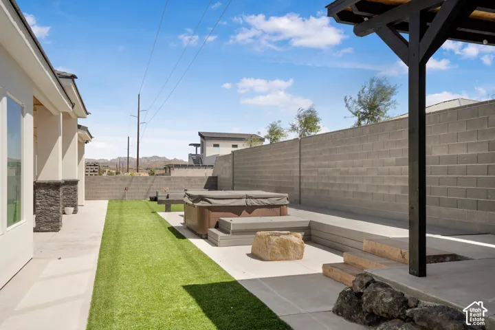 Fenced backyard featuring a patio and a hot tub