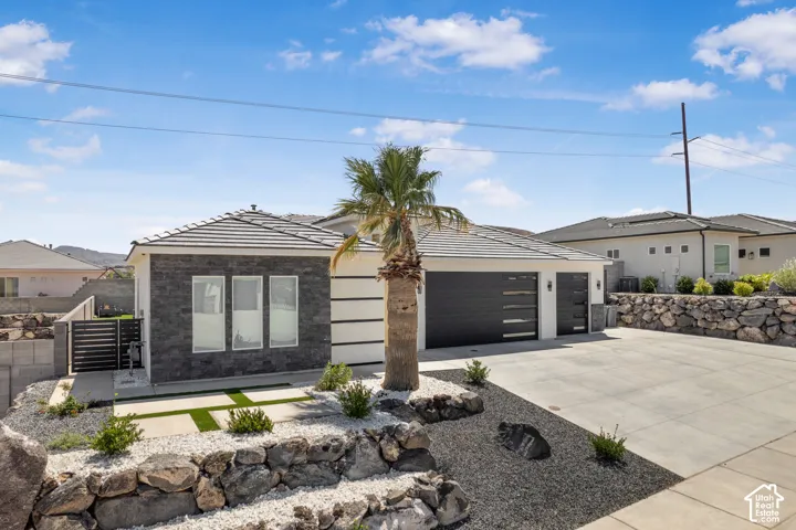 Contemporary house with a garage, driveway, stone siding, and a tiled roof
