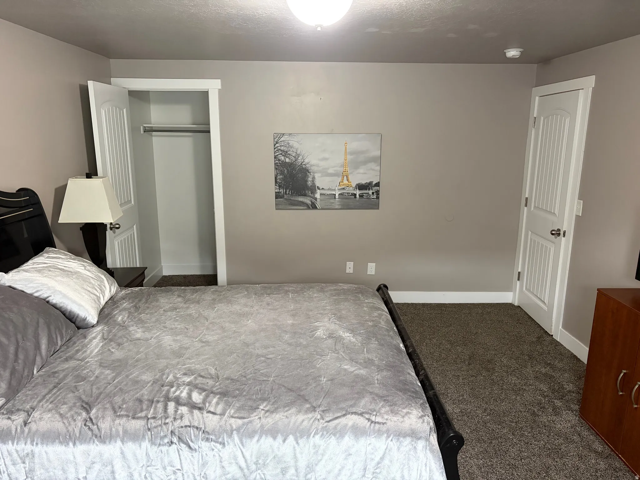 Bedroom with dark colored carpet and a closet