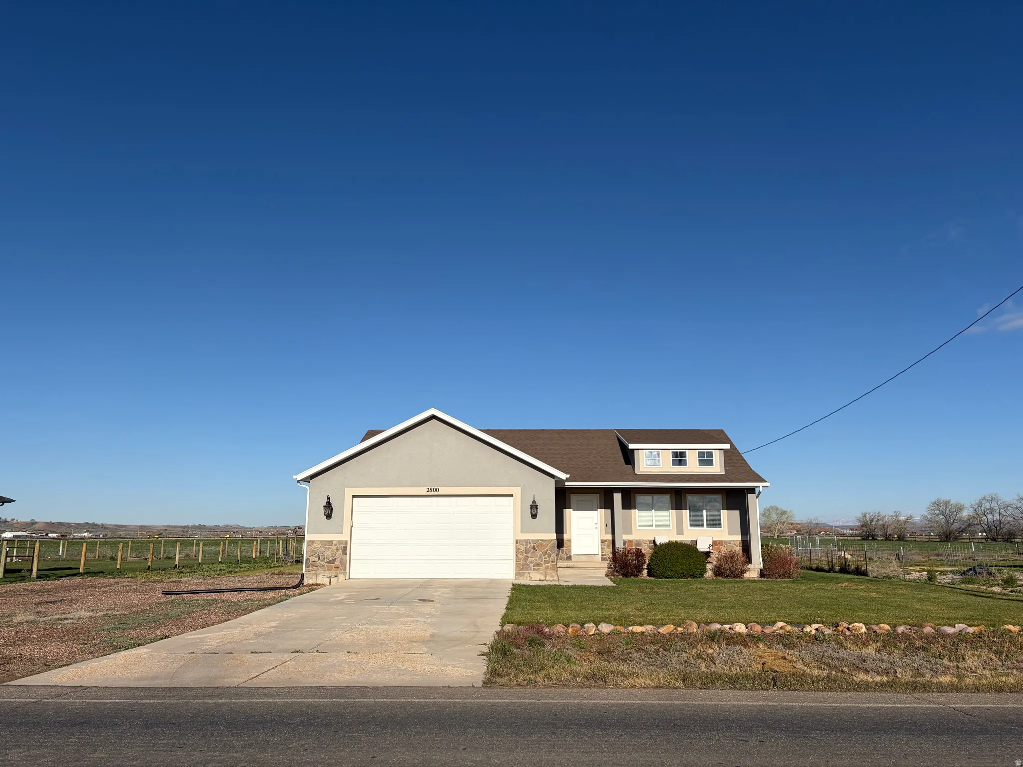 View of front facade featuring concrete driveway, a porch, stone siding, an attached garage, and stucco siding