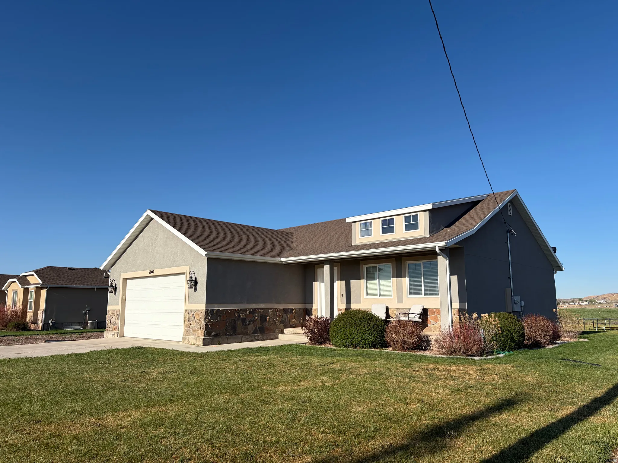 View of front of property with a front lawn, stone siding, stucco siding, and concrete driveway