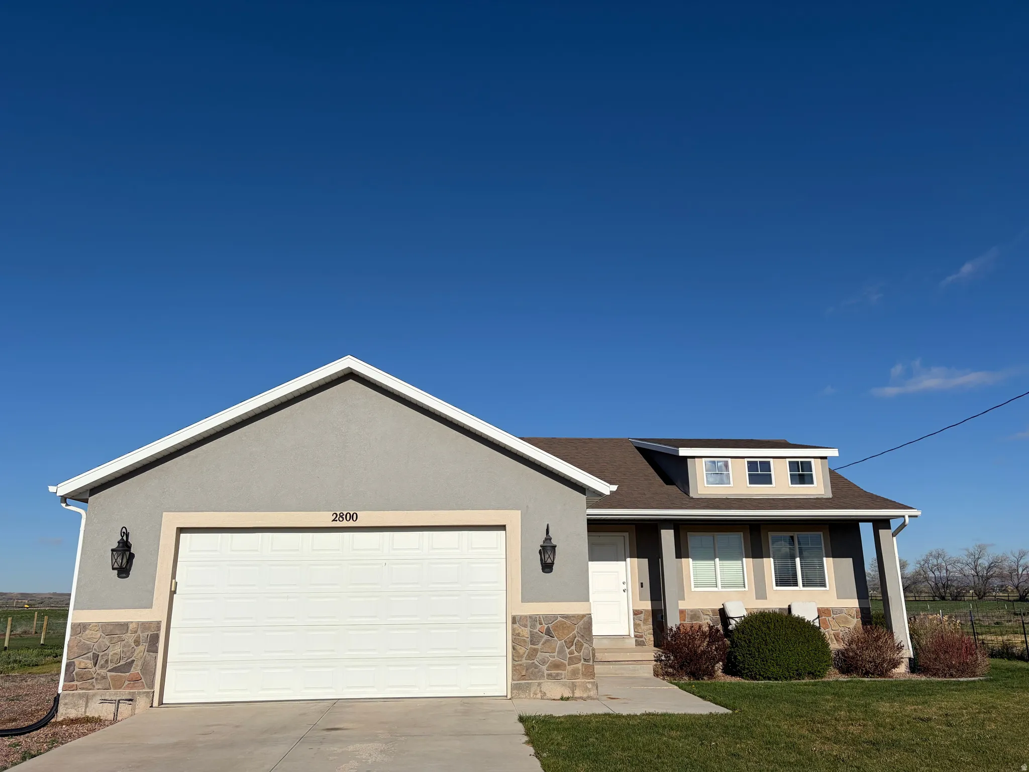 View of front facade with stone siding, concrete driveway, an attached garage, a porch, and stucco siding
