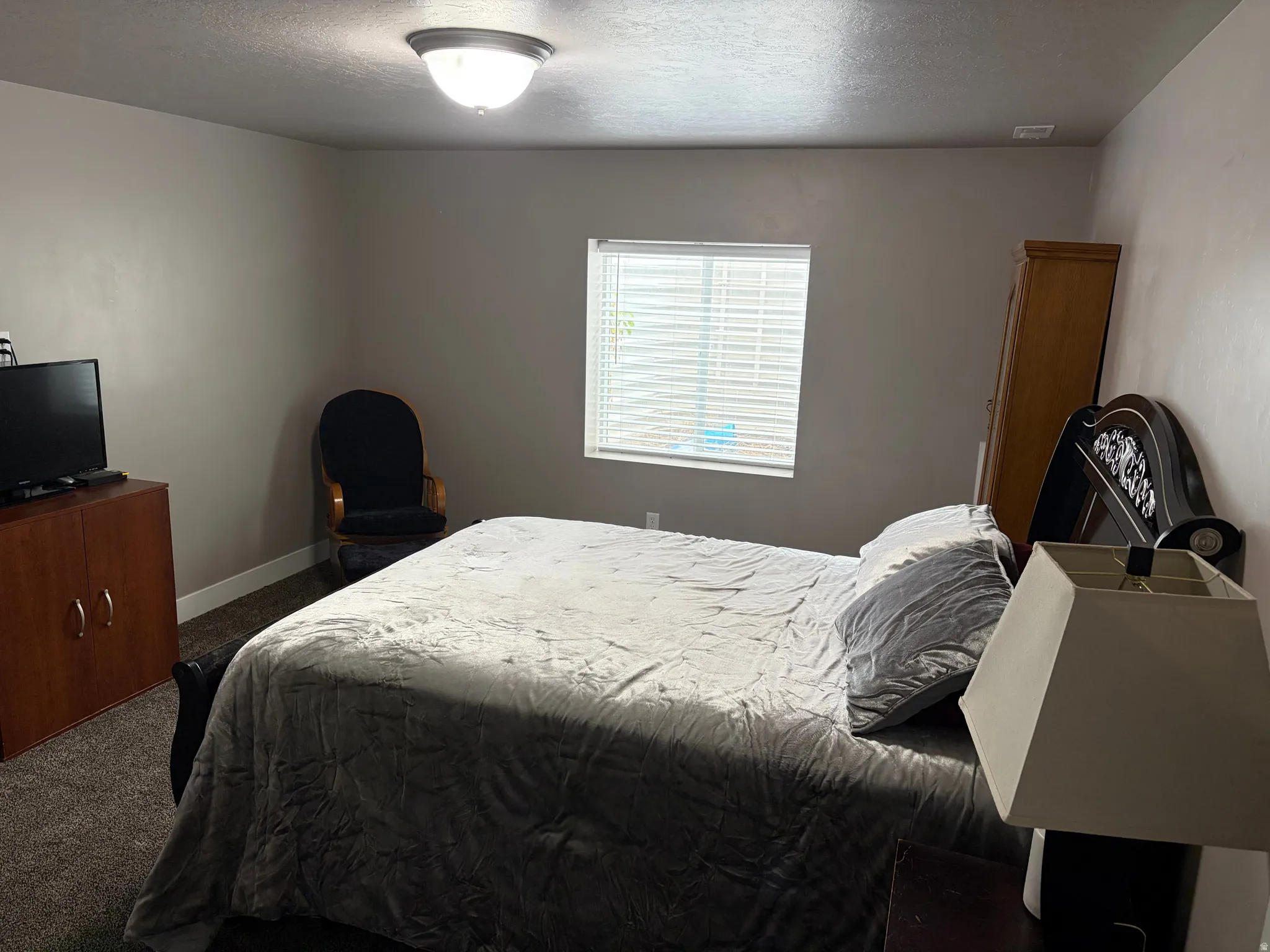 Bedroom with dark carpet and a textured ceiling
