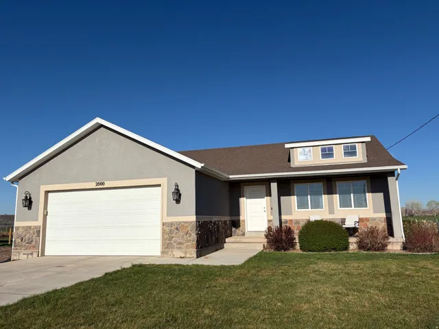 View of front of property with stone siding, a front lawn, and an attached garage