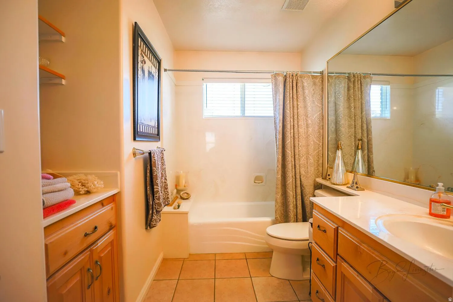 Bathroom with vanity, light tile patterned flooring, shower / bath combination with curtain, and healthy amount of natural light