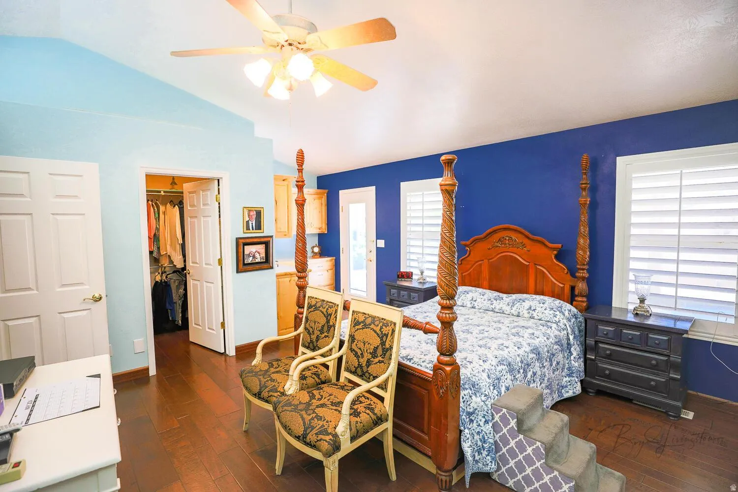Bedroom featuring dark wood-type flooring, a walk in closet, vaulted ceiling, and a ceiling fan