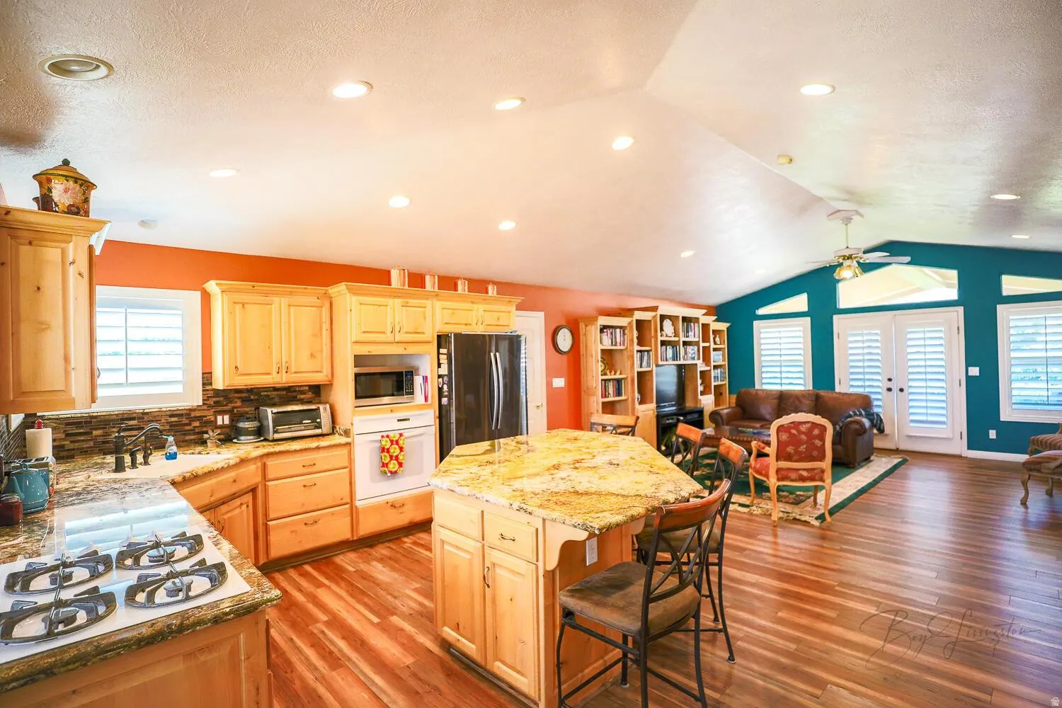 Kitchen featuring light wood finish cabinetry, a breakfast bar, stainless steel appliances, light stone counters, and a center island