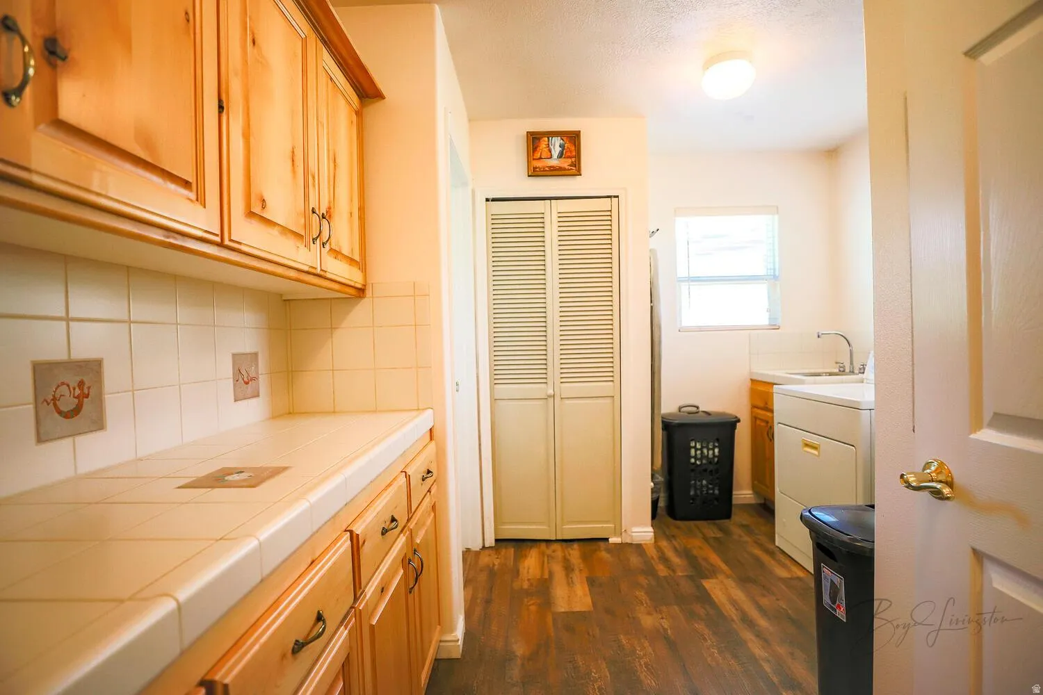 Kitchen featuring tile counters, backsplash, dark wood finished floors, and washer / dryer