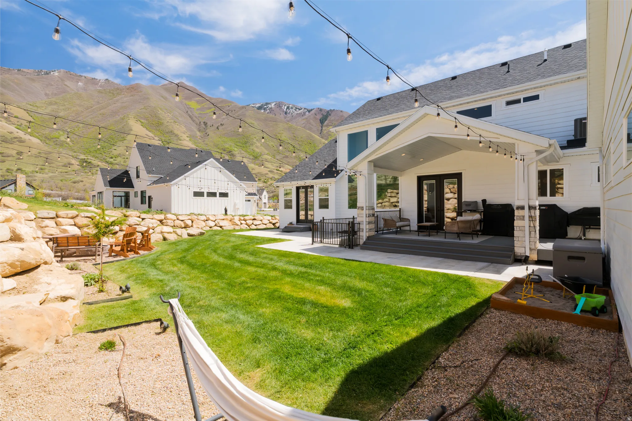 Rear view of property featuring a mountain view, a patio, french doors, a yard, and a shingled roof