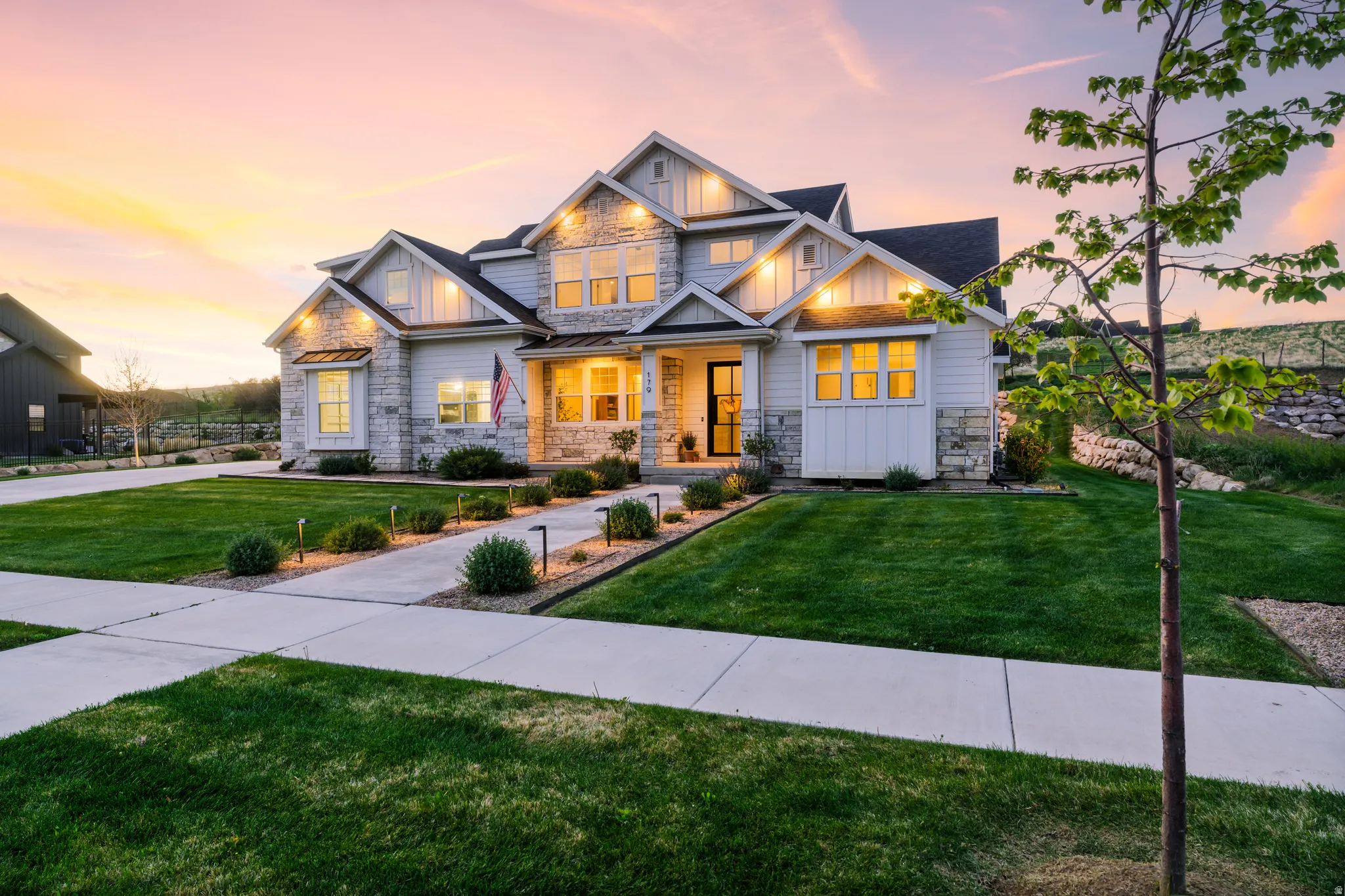 Craftsman-style house with stone siding, board and batten siding, a porch, and a lawn