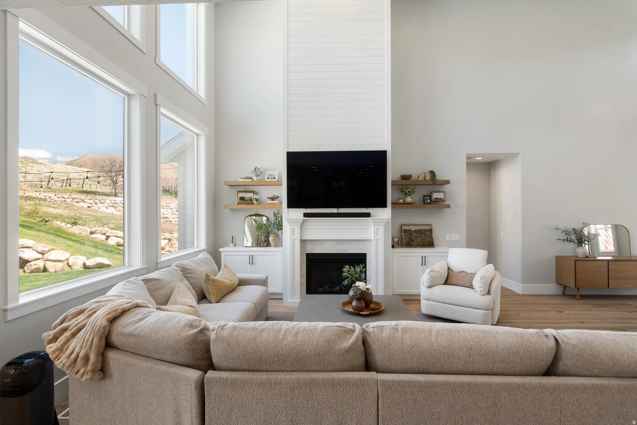 Living room with a high ceiling, wood finished floors, and a fireplace