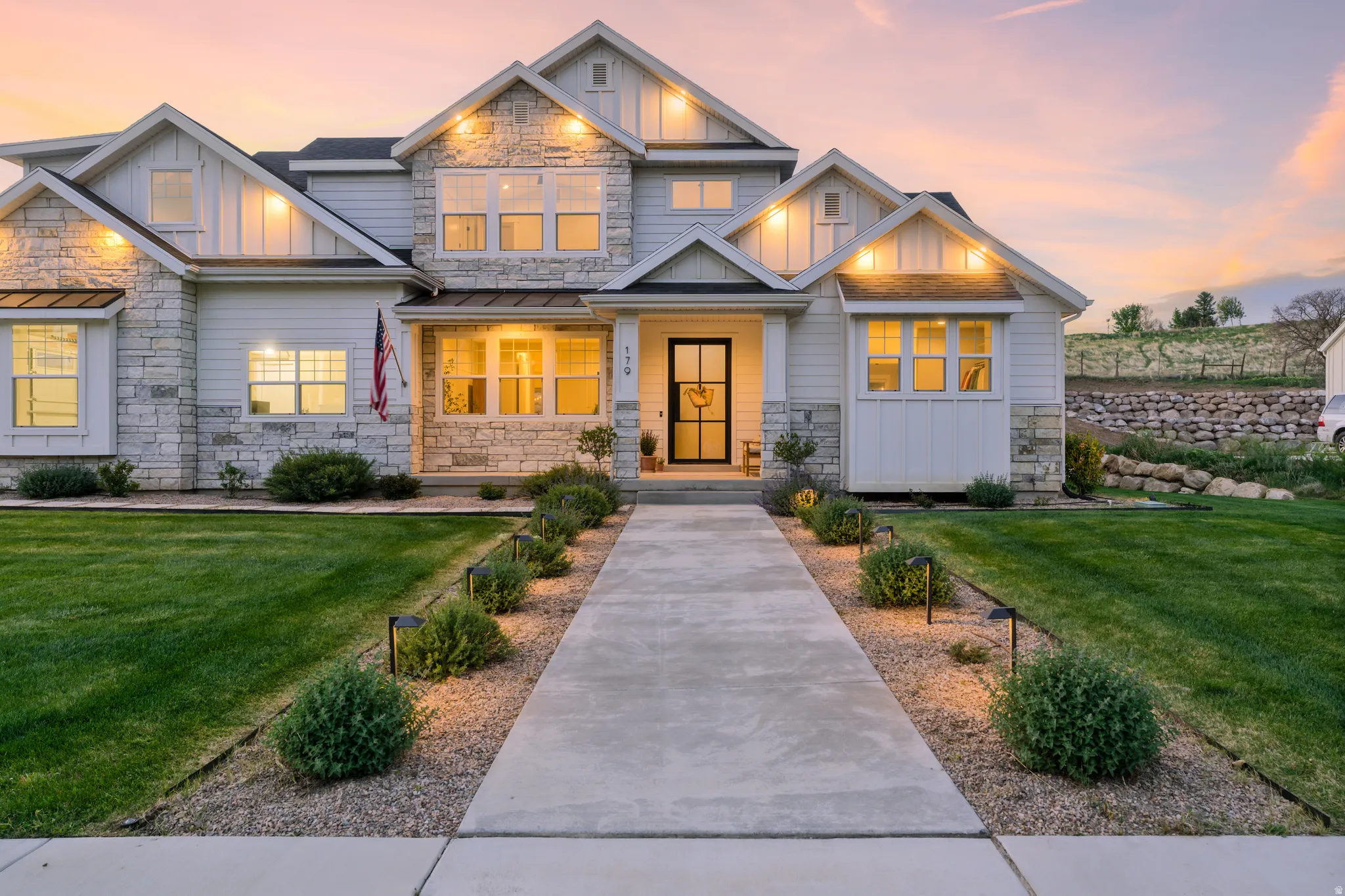Craftsman-style house featuring board and batten siding, stone siding, a front lawn, and a porch