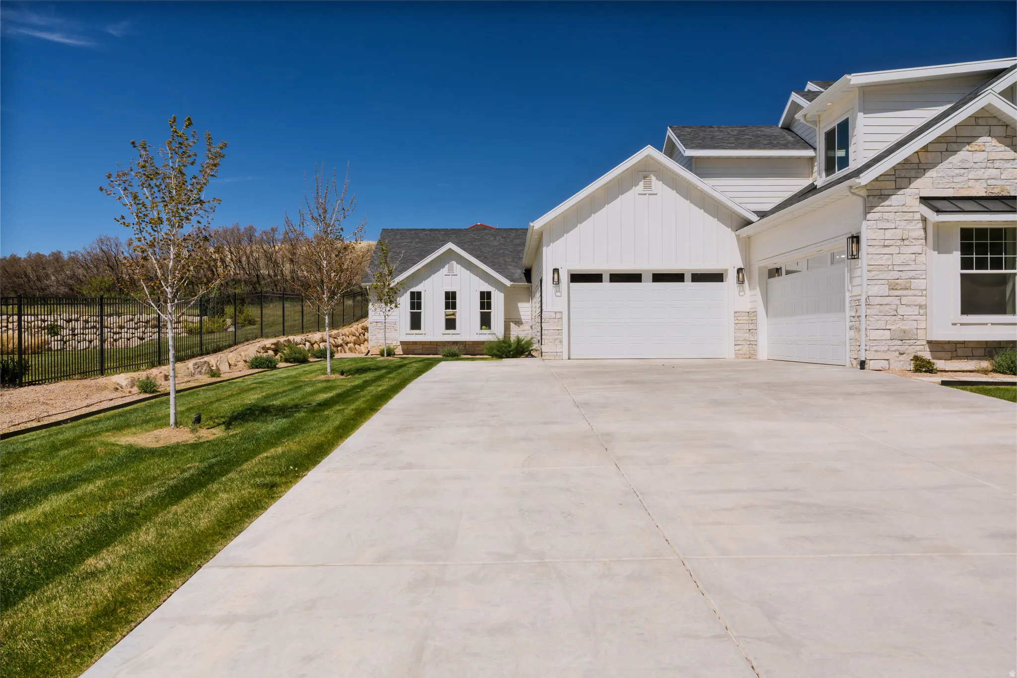 View of front facade with stone siding, concrete driveway, an attached garage, and a shingled roof