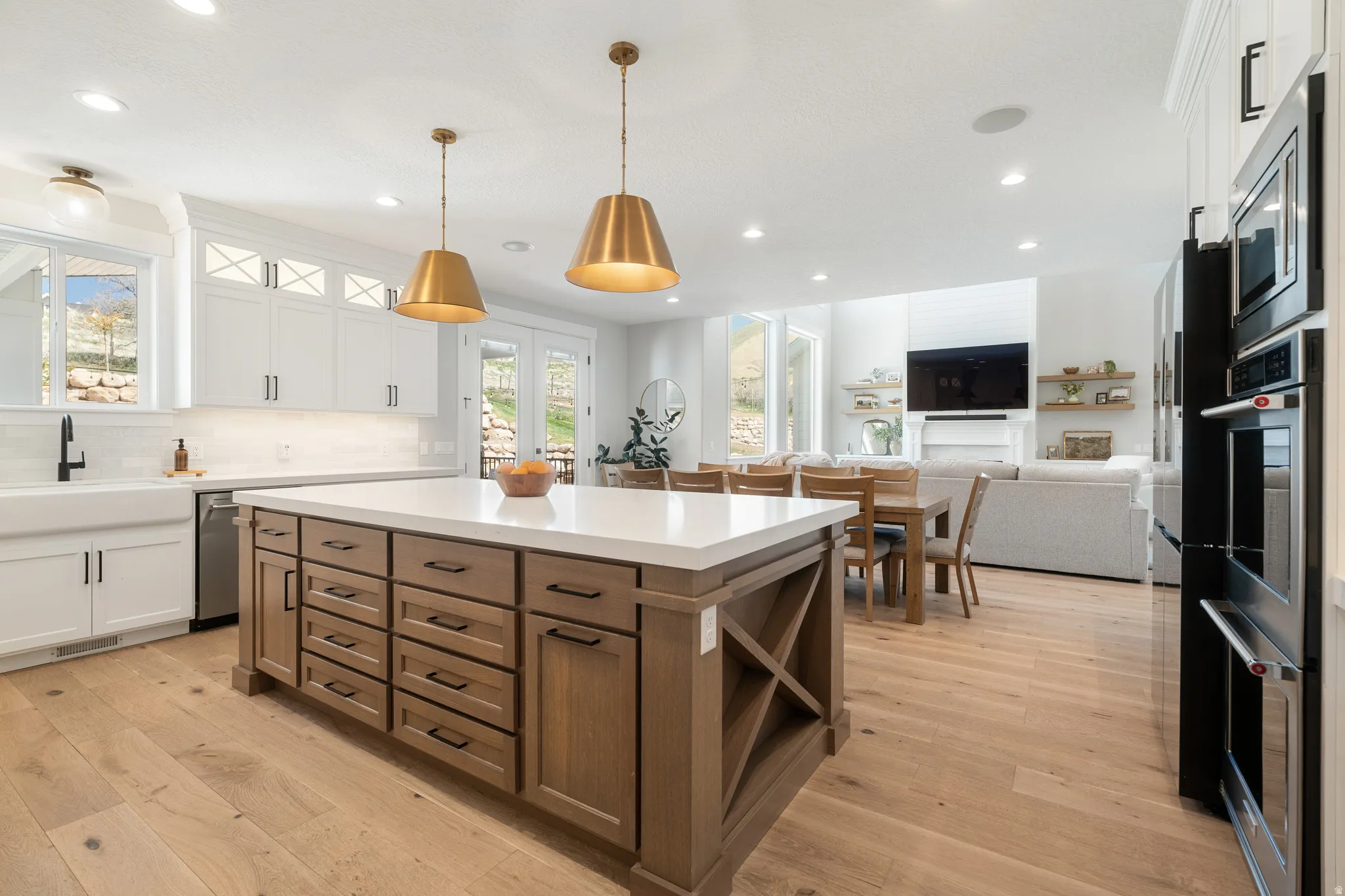 Two tone kitchen with dual tone cabinetry, a kitchen island, open floor plan, light wood-style flooring, and hanging light fixtures